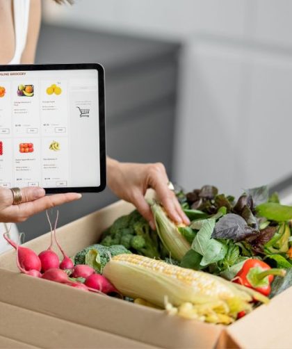 Woman buying groceries online and a package full of food