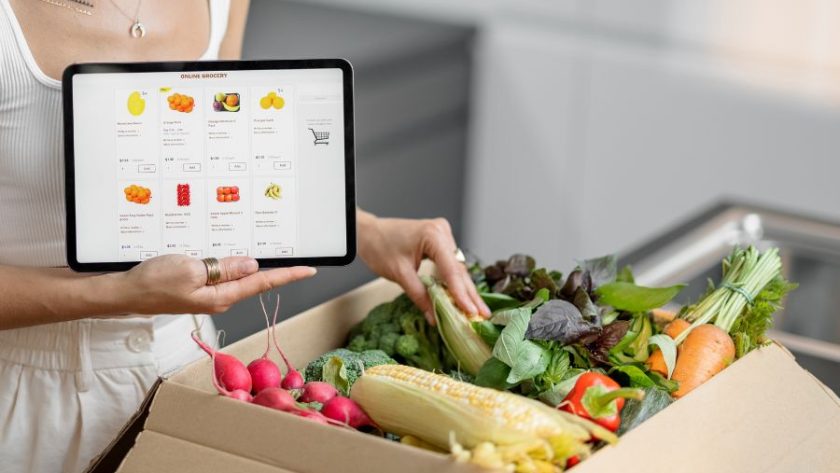 Woman buying groceries online and a package full of food