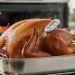“Turkey roasting in an oven with a meat thermometer probe inserted into the thickest part of the thigh.”