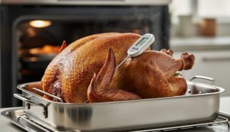 “Turkey roasting in an oven with a meat thermometer probe inserted into the thickest part of the thigh.”